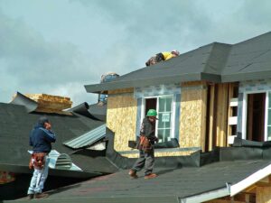 Homeowner sorting asphalt shingles, metal flashing, and roofing felt into separate covered containers.