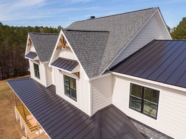 Attic rafters and roof decking with dark moisture stains, softened wood, and a flashlight inspection